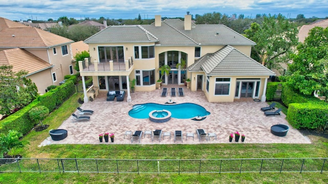 rear view of house featuring a patio area, a yard, a balcony, an outdoor fire pit, and an in ground hot tub