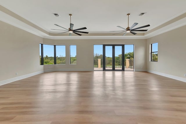 unfurnished room with ornamental molding, ceiling fan, light wood-type flooring, and a tray ceiling