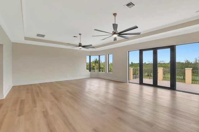 unfurnished room featuring ceiling fan, light wood-type flooring, ornamental molding, and a raised ceiling