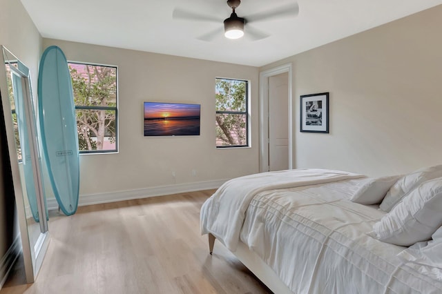 bedroom with multiple windows, ceiling fan, and light wood-type flooring