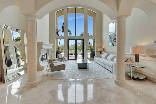 living room with a towering ceiling, french doors, and decorative columns