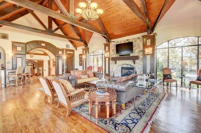 living room with beamed ceiling, high vaulted ceiling, a chandelier, and a fireplace