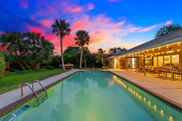 pool at dusk featuring outdoor lounge area and a patio