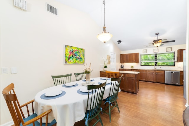 dining area with light wood-style floors, ceiling fan, vaulted ceiling, and visible vents
