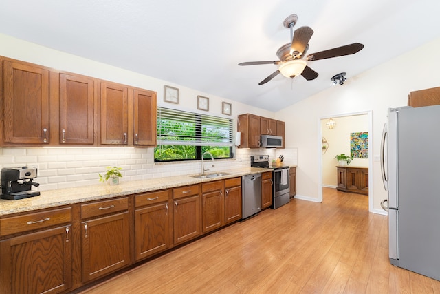 kitchen with appliances with stainless steel finishes, sink, backsplash, light hardwood / wood-style floors, and lofted ceiling