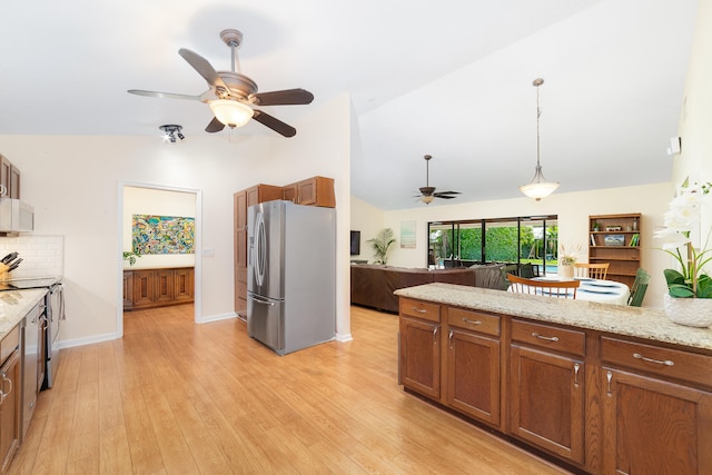 kitchen with vaulted ceiling, decorative light fixtures, stainless steel appliances, and light hardwood / wood-style floors