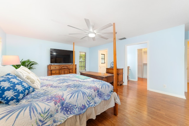 bedroom with a closet, ceiling fan, light wood-type flooring, and a walk in closet