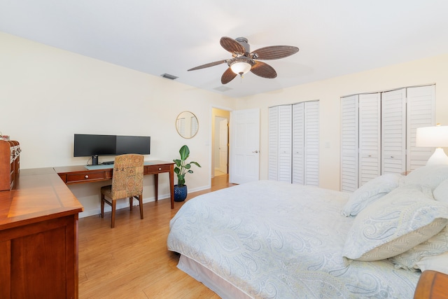 bedroom featuring two closets, light wood-type flooring, and ceiling fan