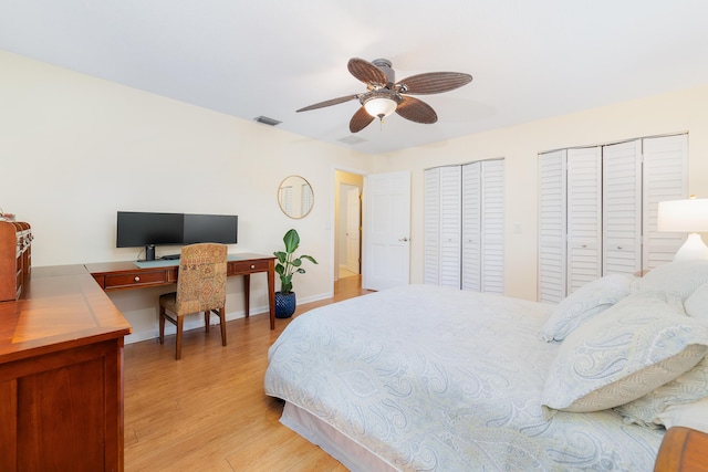 bedroom featuring light wood finished floors, two closets, a ceiling fan, baseboards, and visible vents