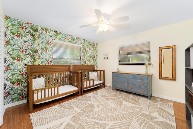 bedroom featuring a ceiling fan, baseboards, wallpapered walls, and wood finished floors