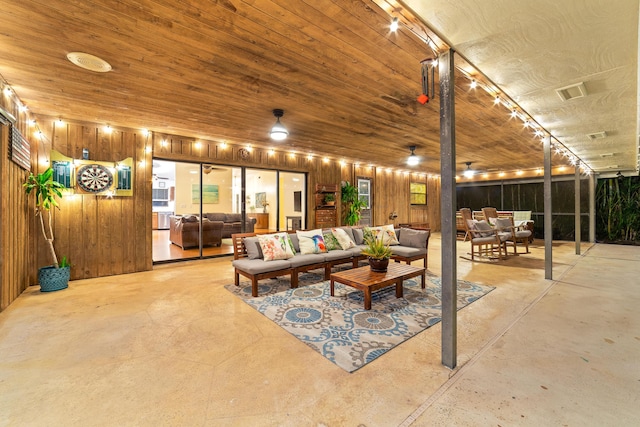 living area featuring wooden walls and concrete floors