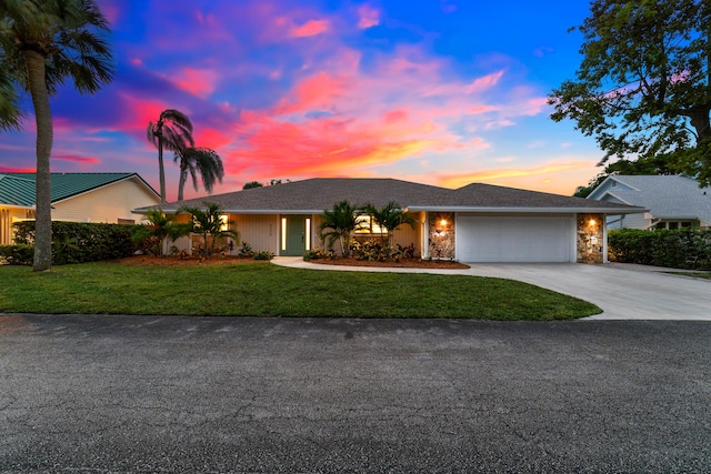 ranch-style home featuring a garage, stone siding, driveway, and a front yard