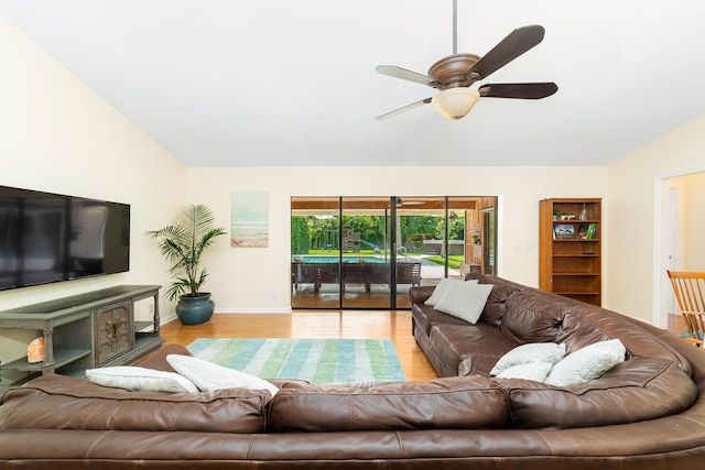 living area featuring wood finished floors, a ceiling fan, baseboards, and lofted ceiling