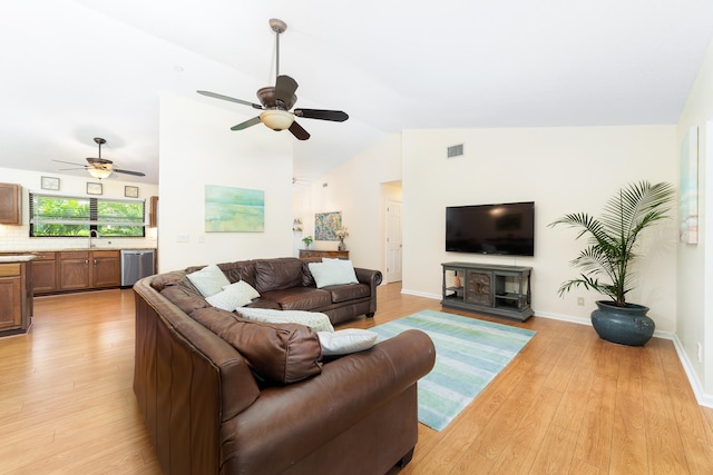 living room with sink, ceiling fan, vaulted ceiling, and light wood-type flooring