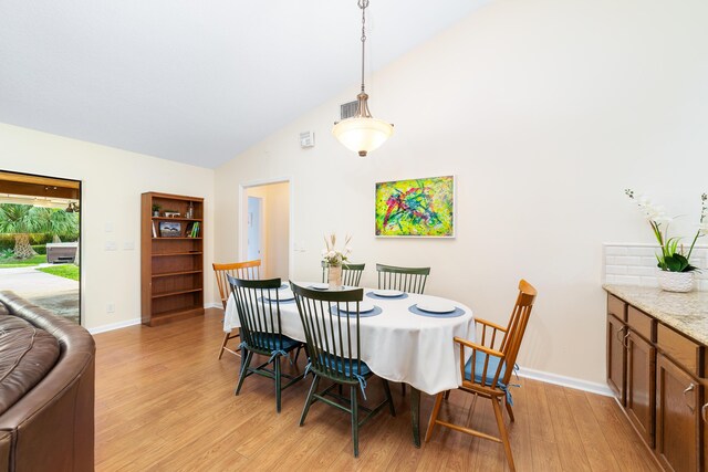 dining area featuring baseboards, light wood finished floors, high vaulted ceiling, and visible vents