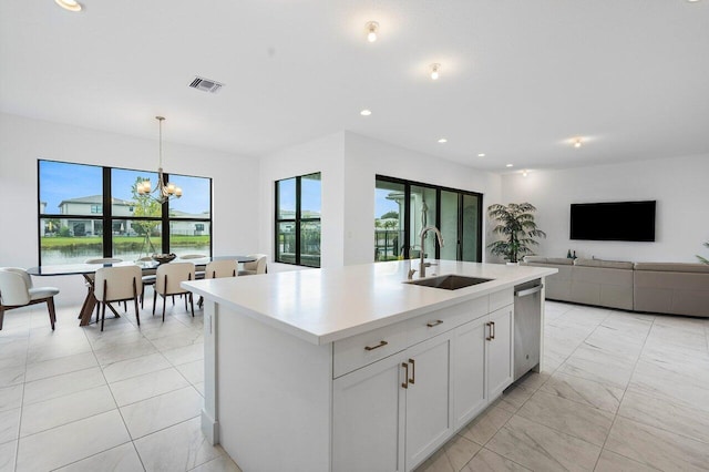 kitchen featuring an island with sink, sink, white cabinetry, a chandelier, and decorative light fixtures