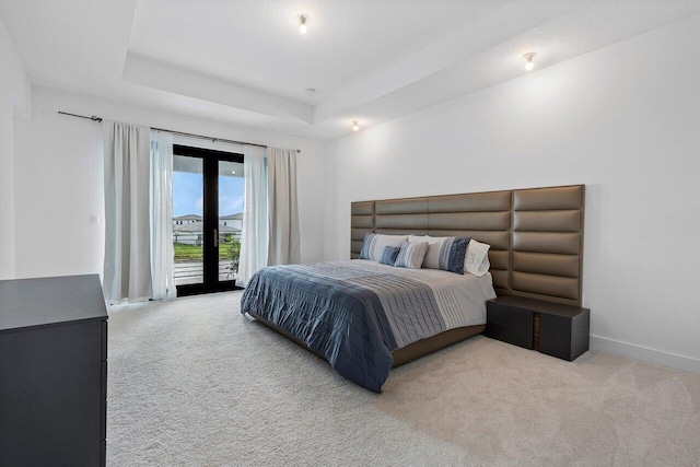 bedroom with light carpet, a raised ceiling, and french doors