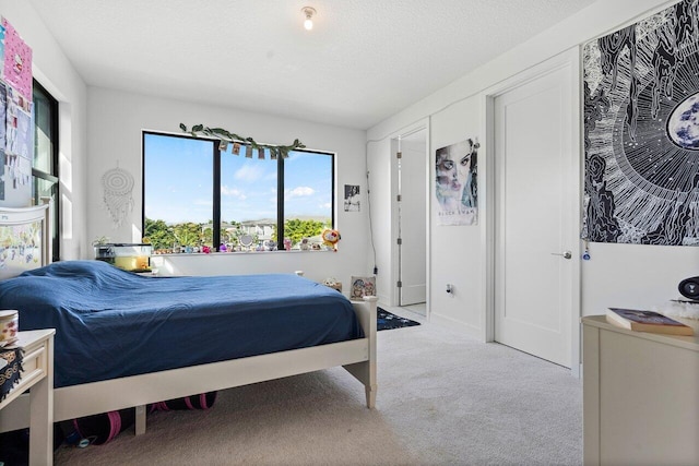 bedroom with light colored carpet and a textured ceiling