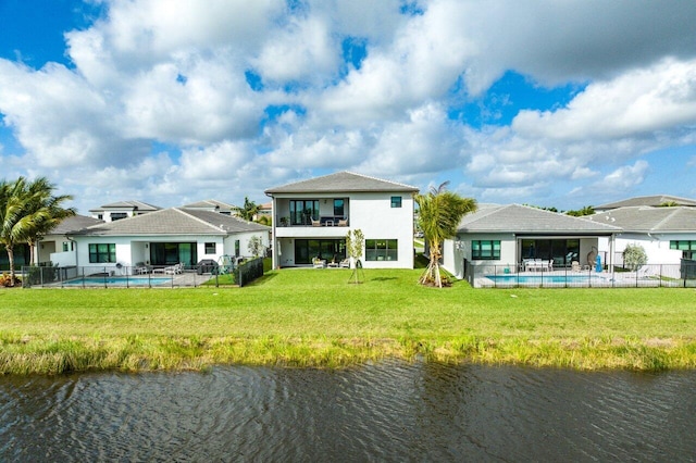 back of house with a water view, a patio, and a yard