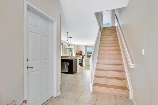 stairway featuring tile patterned floors and a notable chandelier