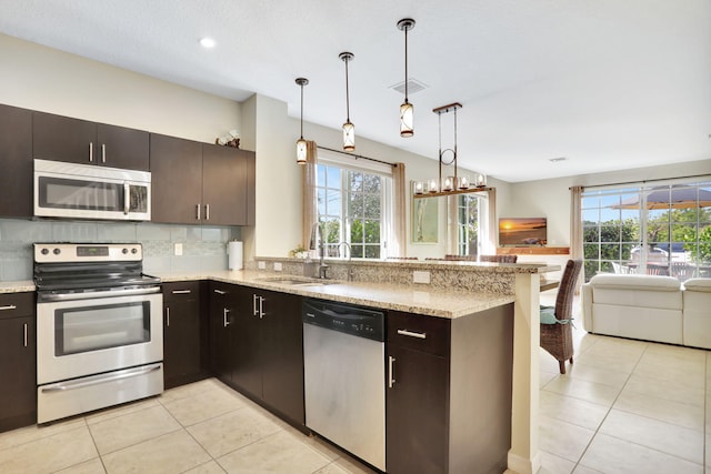 kitchen with kitchen peninsula, dark brown cabinetry, stainless steel appliances, and hanging light fixtures