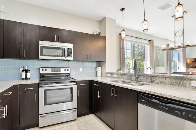 kitchen with dark brown cabinetry, stainless steel appliances, tasteful backsplash, and sink