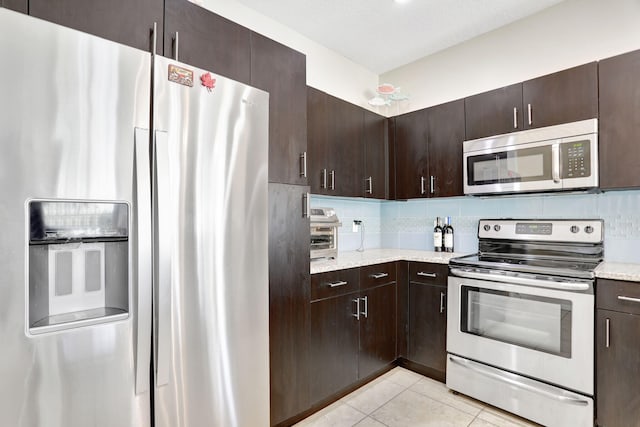 kitchen featuring tasteful backsplash, dark brown cabinets, light tile patterned floors, and stainless steel appliances