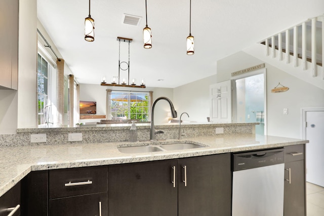 kitchen featuring pendant lighting, an inviting chandelier, sink, stainless steel dishwasher, and light stone countertops