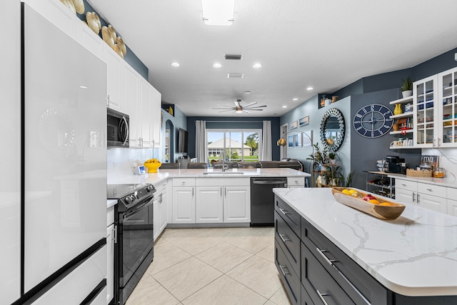 kitchen with appliances with stainless steel finishes, light stone counters, sink, and white cabinets