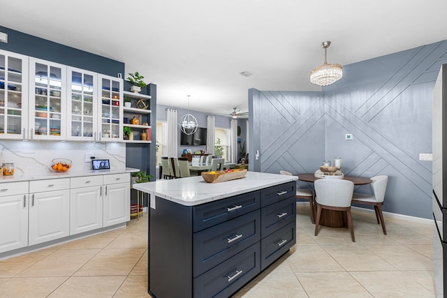 kitchen with a center island, decorative backsplash, hanging light fixtures, white cabinets, and light tile patterned floors