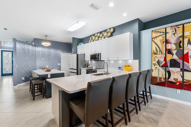 kitchen featuring kitchen peninsula, white cabinetry, appliances with stainless steel finishes, decorative light fixtures, and a kitchen breakfast bar