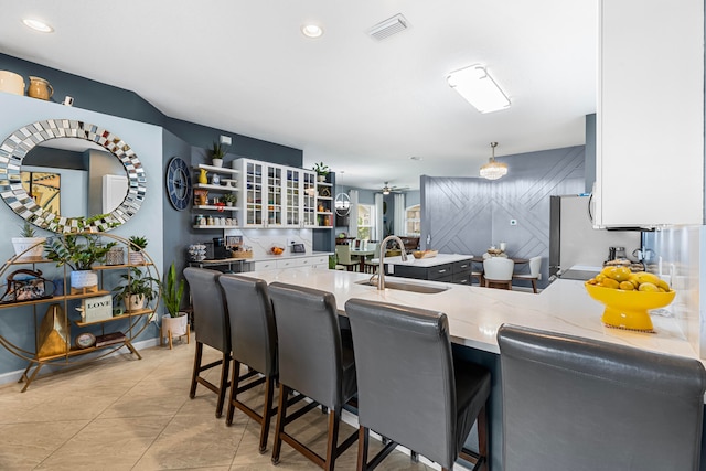 kitchen featuring ceiling fan, white cabinets, sink, kitchen peninsula, and a kitchen breakfast bar