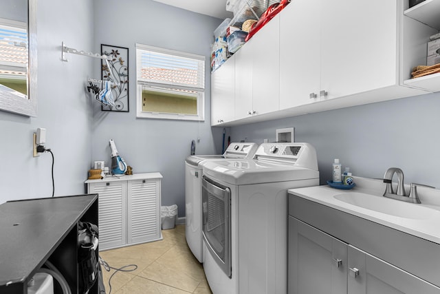 clothes washing area with washer and dryer, light tile patterned flooring, cabinets, and sink