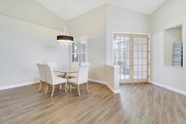 dining area featuring french doors, a notable chandelier, high vaulted ceiling, and light wood-type flooring