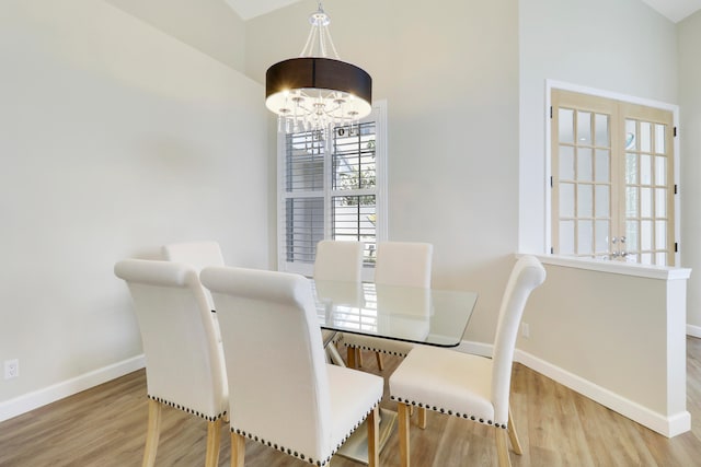 dining room with vaulted ceiling, light hardwood / wood-style flooring, and a chandelier