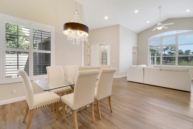 dining room with light hardwood / wood-style flooring, ceiling fan with notable chandelier, and vaulted ceiling