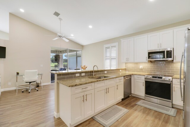 kitchen featuring a wealth of natural light, sink, appliances with stainless steel finishes, and kitchen peninsula