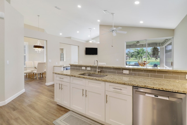 kitchen with lofted ceiling, white cabinets, light stone countertops, dishwasher, and sink