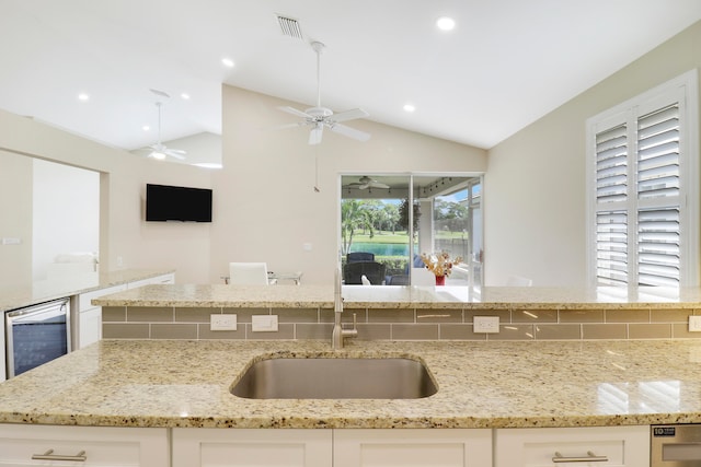 kitchen featuring white cabinetry, light stone counters, and vaulted ceiling