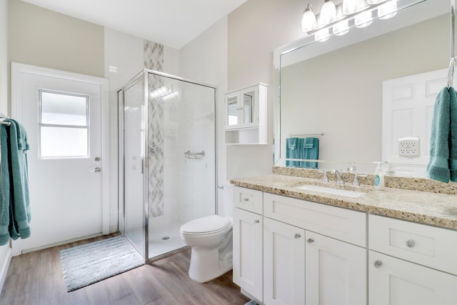 bathroom featuring vanity, toilet, a shower with shower door, and hardwood / wood-style floors