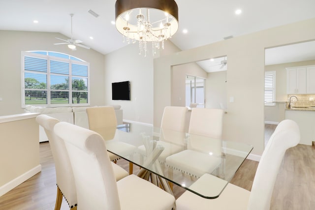 dining room with sink, vaulted ceiling, ceiling fan with notable chandelier, and light wood-type flooring