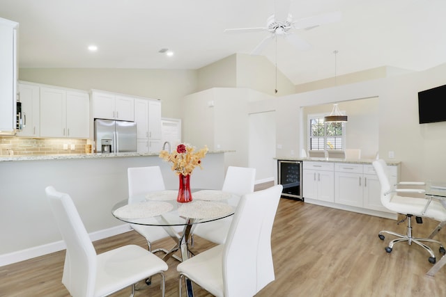 dining area with wine cooler, high vaulted ceiling, light hardwood / wood-style floors, and ceiling fan