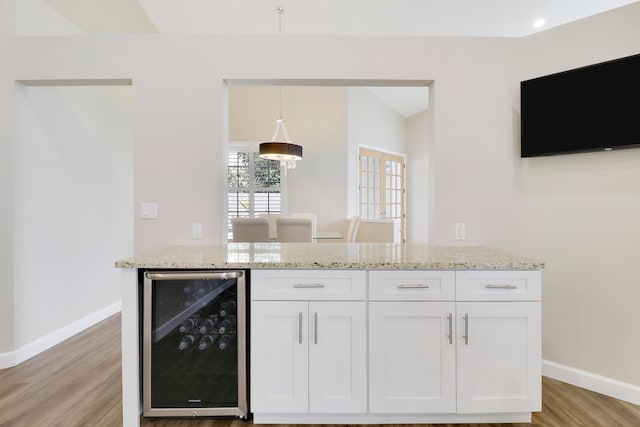 kitchen featuring wine cooler, white cabinets, decorative light fixtures, and light wood-type flooring