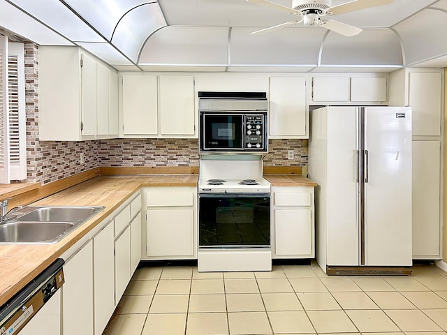 kitchen featuring white appliances, sink, decorative backsplash, light tile patterned floors, and white cabinetry