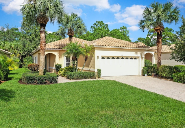 mediterranean / spanish-style home featuring a front lawn and a garage