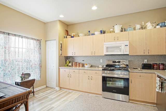 kitchen with light wood-type flooring, light brown cabinets, stainless steel appliances, and tasteful backsplash