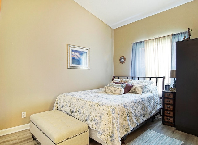 bedroom with hardwood / wood-style floors and vaulted ceiling