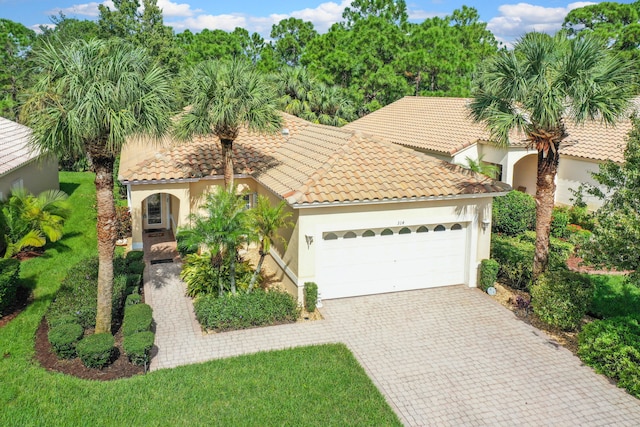 mediterranean / spanish home with a garage and a front lawn