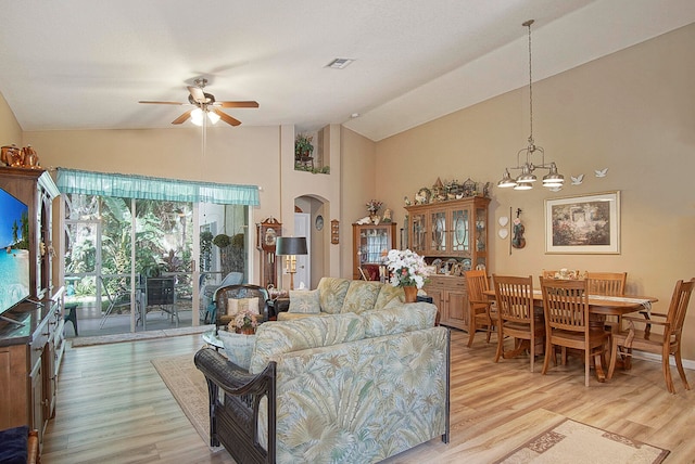 living room featuring ceiling fan with notable chandelier, light hardwood / wood-style floors, and high vaulted ceiling