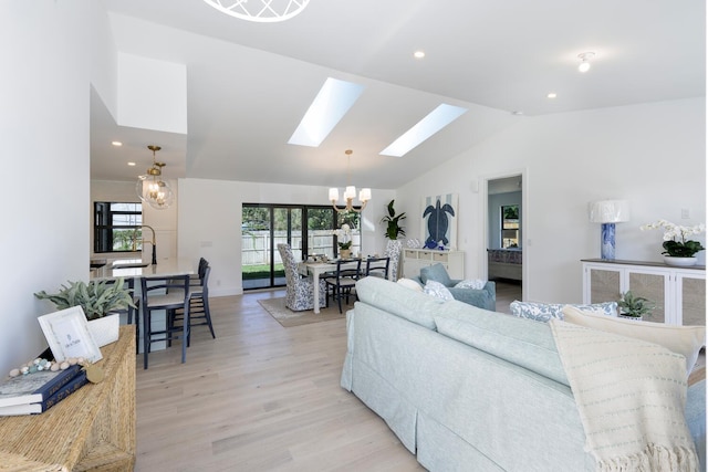 living room featuring plenty of natural light, light hardwood / wood-style flooring, lofted ceiling with skylight, and a notable chandelier